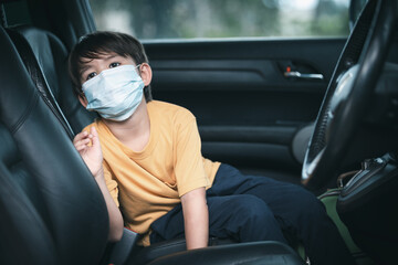 A cute little boy wearing a protective face mask in car after school during the epidemic.Mental health concept.State of mind.