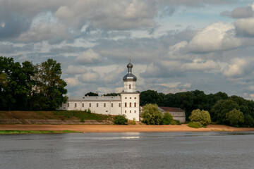 View of the wall of the St. George (Yuriev) Monastery and the Mikhailovsky Tower from the Volkhov River on a sunny summer day with cumulus clouds, Veliky Novgorod, Russia