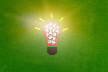 Electric light bulb, puzzle pieces on a green background. The concept of the development of creative ideas.