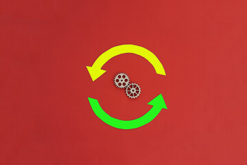 Two round yellow and green arrows, a pair of wooden gears on a red background. The concept of interaction, promotion.