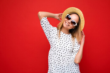 Attractive smiling joyful young blonde woman wearing everyday stylish clothes and modern sunglasses isolated on colorful background wall looking at camera