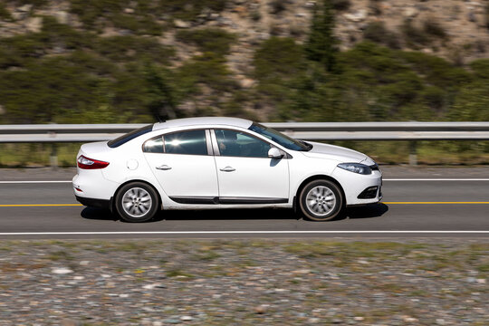 Novosibirsk, Russia - August 08, 2021:   .white Renault Fluence   driving fast on freeway in highlands on summer day on background forest