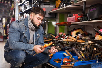 Adult serious consumer is choosing file and screwdriver in store