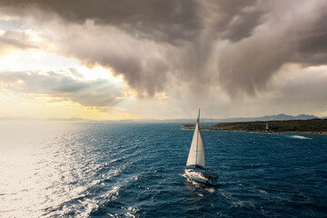View from above, stunning aerial view of a sailboat sailing on a blue water during a beautiful and...