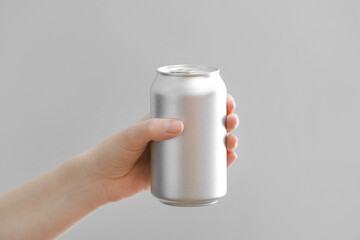 Hand with can of soda on grey background