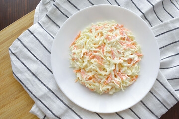 Coleslaw salad with carrot and cabbage on a white plate.