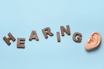 Word HEARING and model of ear on color background