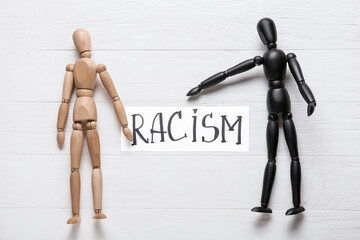 Different mannequins on white wooden background. Racism concept