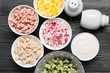 Bowls with different ingredients for okroshka on dark wooden background