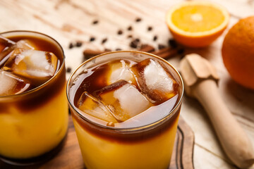 Glasses with cold orange juice on light wooden background, closeup