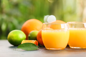 Glasses of tasty orange juice on table outdoors, closeup