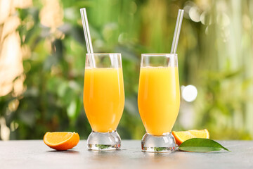 Glasses of tasty orange juice on table outdoors