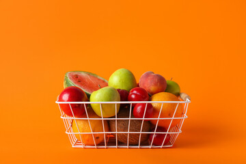 Basket with fresh fruits on color background