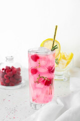 Glass of tasty raspberry lemonade on light background