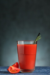 Glass of tasty tomato juice on dark background