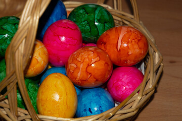 close-up of hand-made colored easter eggs in wicker basket ready to eat