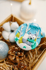 Gift box with cute Christmas toy and pine cone. Close up of festive souvenir with arctic fox made...