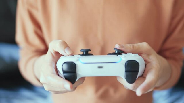 Closeup - Hands holding controller presses buttons on game joystick and play TV game.