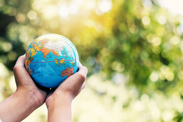 A young woman holding a globe with both hands-on nature backgrounds.