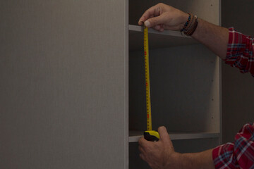 carpenter measuring the cupboard with the meter