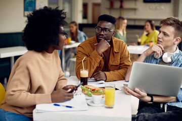 African American student and his friends study on lunch break in cafeteria.