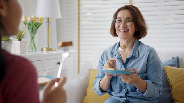 Asia elder people, latin lady parent or friendly mum enjoy fun chat with best friend or guest sitting relax at home on sofa couch drink afternoon tea or coffee in good warm sweet time wellness life.