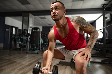 Fototapeta na wymiar Portrait of man bodybuilder in red shirt in gym