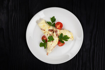 Omelet with Ham and Cheese on black wooden background