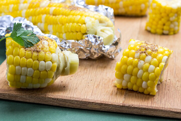 Boiled corn  and boiled corn in foil on wooden board