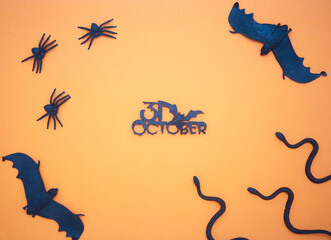 The inscription October 31 on an orange background, the concept of the holiday Halloween, day of the dead, carnival background, snakes, spiders and bats on a bright background.
