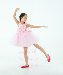 Naklejka premium Isolated full body studio shot of little cute pretty Asian ballerina kid wears pink beautiful roses flowers ballet dress and red shoes smiling posing dancing happily in front of white background