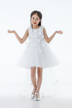 Portrait isolated studio shot of little Asian cute ballerina kid in pink beautiful ballet dress with high heels standing smiling posing elegance gesture in front white background