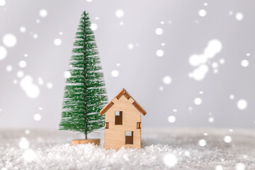 Obraz na płótnie Canvas Model of a wooden house near a miniature Christmas tree