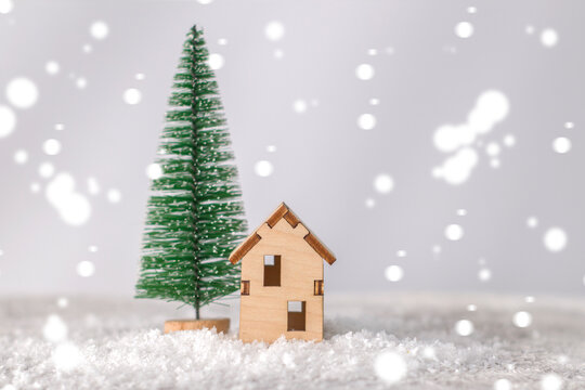 Model of a wooden house near a miniature Christmas tree