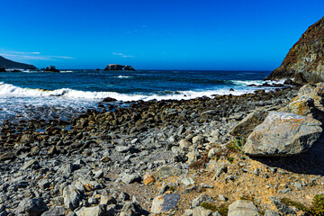 Fototapeta na wymiar Looking out from a rocky beach to an arched rock on the California coast