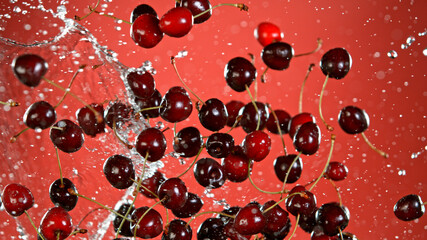 Fresh cherries flying in the air, red gradient background.