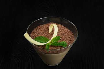 Delicious Italian dessert tiramisu, on a black wooden background decorated with mint leaf, with copy space.
