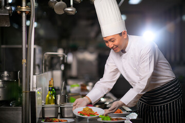 Asian Male chef presenting the dish in the kitchen. Selective focus.