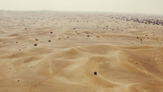 Off road sand buggy driving in immense open Arabic desert, travel activity, aerial