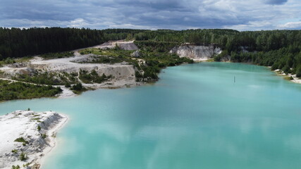 A girl in a dress floats on a glanders board on a pond with bright turquoise water. Warm summer day for travel. Top view from a quadcopter. Aerial photography