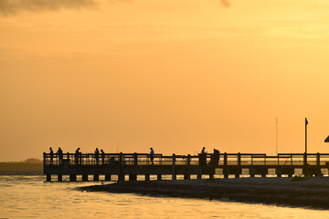 Obraz premium People fishing on a pier in Sanibel Island, Florida at sunrise.
