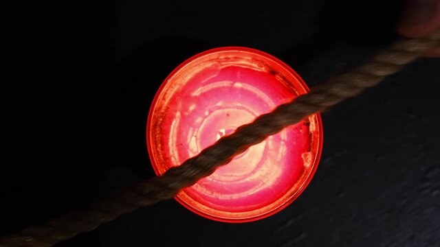 Burning a jute rope on the fire of a candle for the shibari ritual.