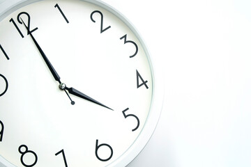 A wall clock that announces 5 o'clock on the hour