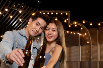 happy asian teenager couple man and woman in love drinking beer alcohol and toasting bottle in celebration party. young happy couple love and romantic at first date.