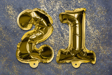 The number of the balloon made of golden foil, the number twenty-one on a gray background with...