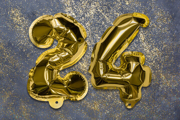 The number of the balloon made of golden foil, the number twenty-four on a gray background with sequins. Birthday greeting card with inscription 24. Numerical digit, Celebration event, template.