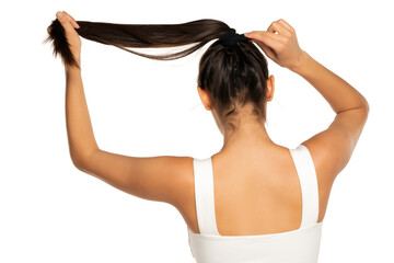 Back view of a young woman adjusting her hair in a ponytail