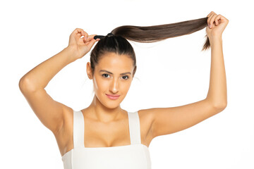 Young smiling woman adjusting her hair in a ponytail
