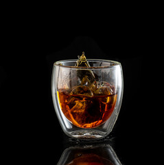 splash in double walled glass with whiskey with ice on black background