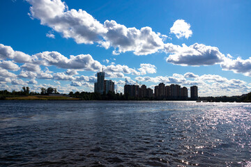 Fototapeta premium Cityscape of bay, buildings and blue sky with white cumulus clouds